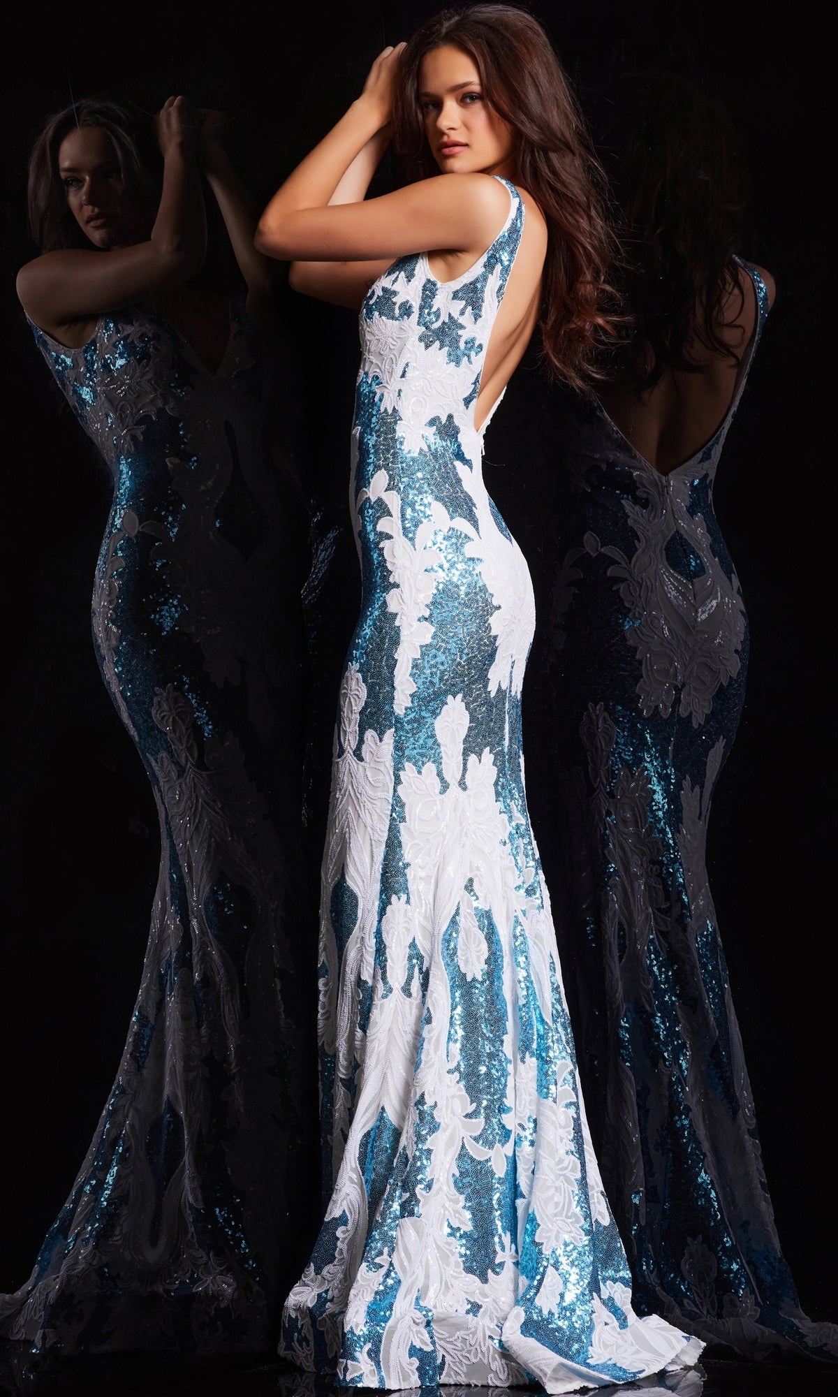 A woman models the Jovani V-Back Long Sequin-Print Prom Dress 23319, a sleeveless, backless blue and white gown, posing in front of a mirror to display the dress from multiple angles.